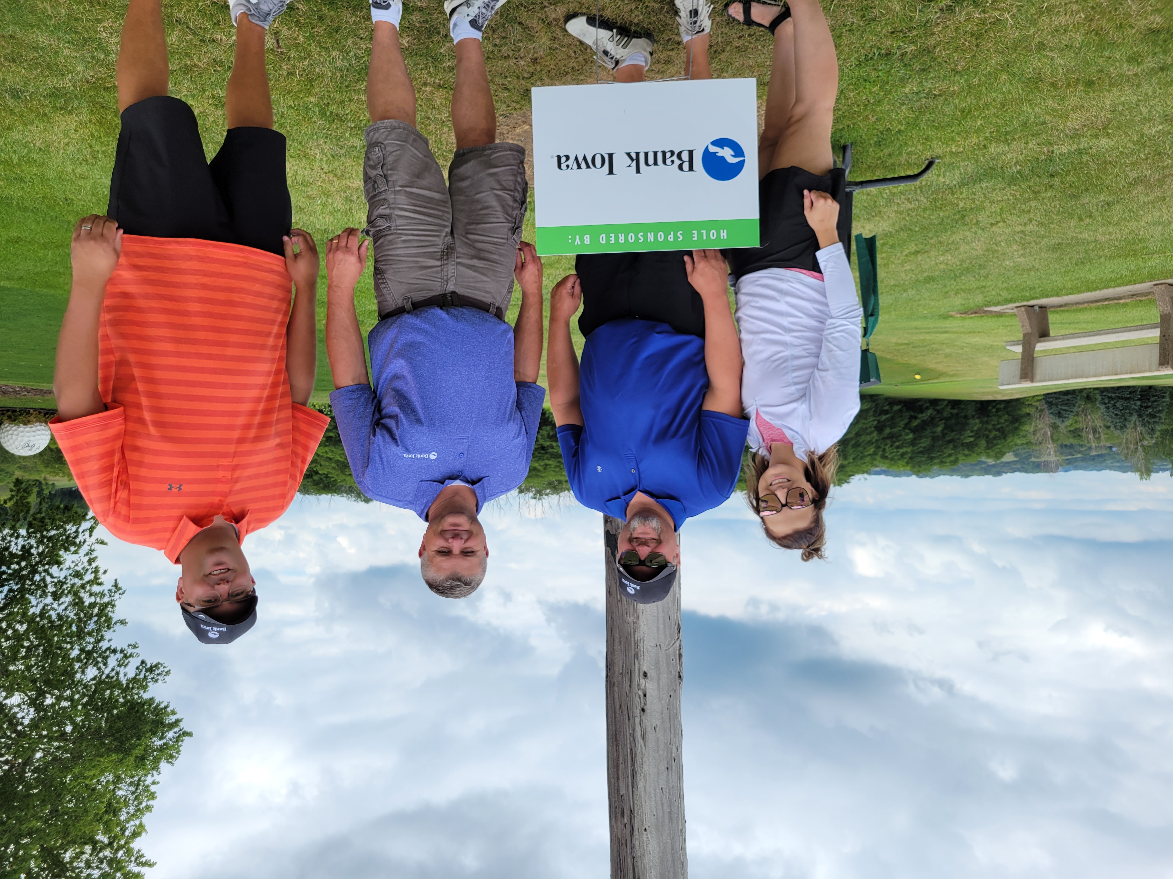 Four people standing on a golf course smiling