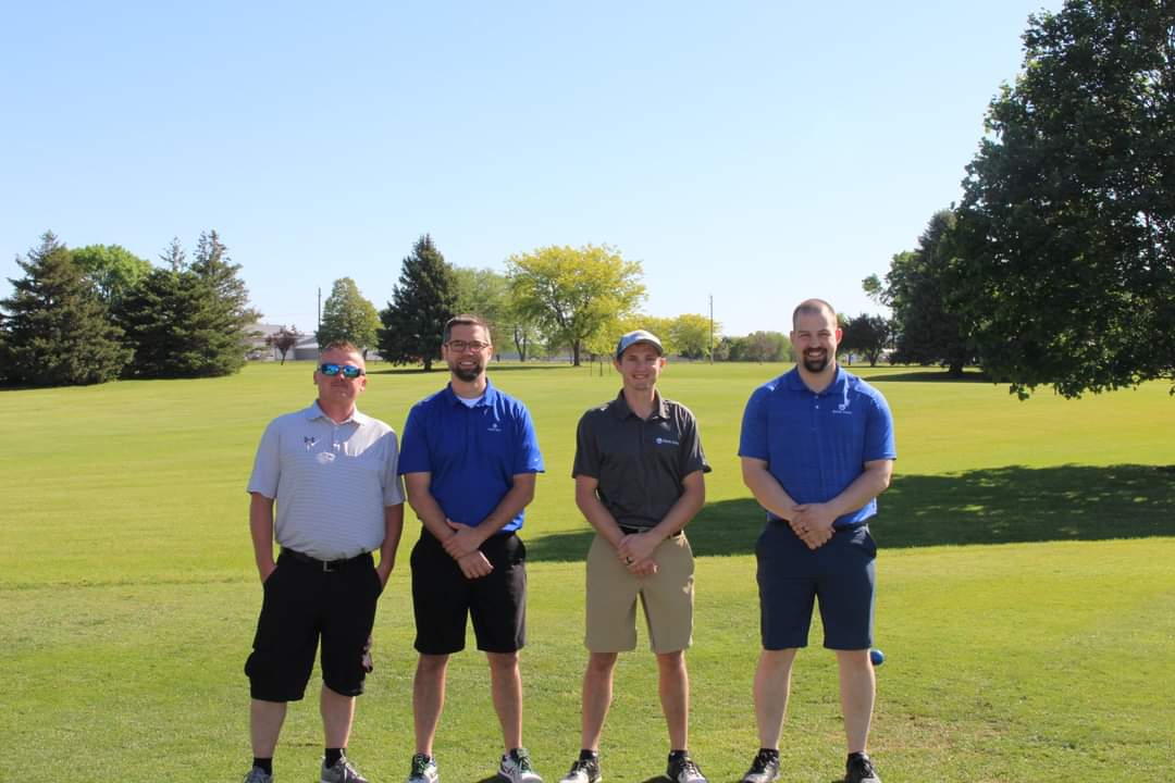 Men standing on golf course smiling