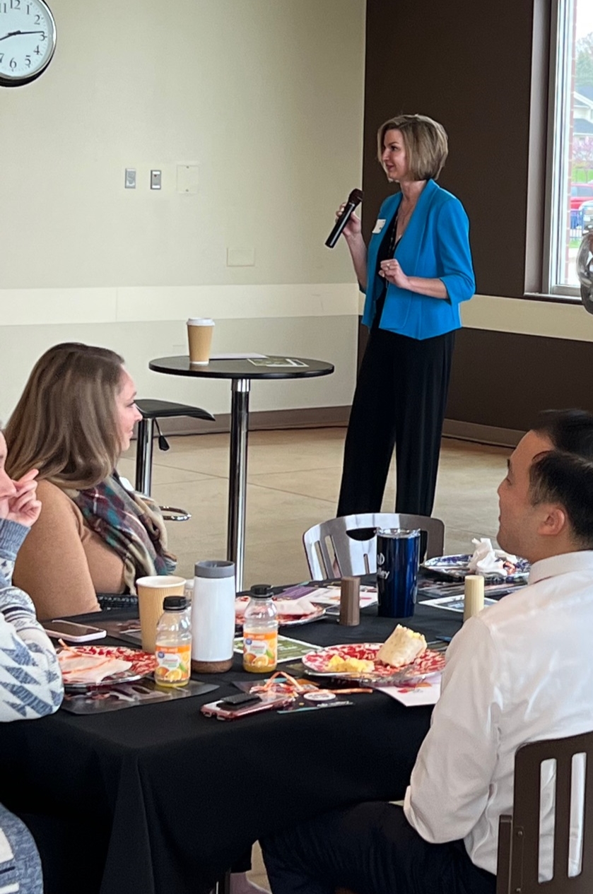 Woman talking into microphone to table of people